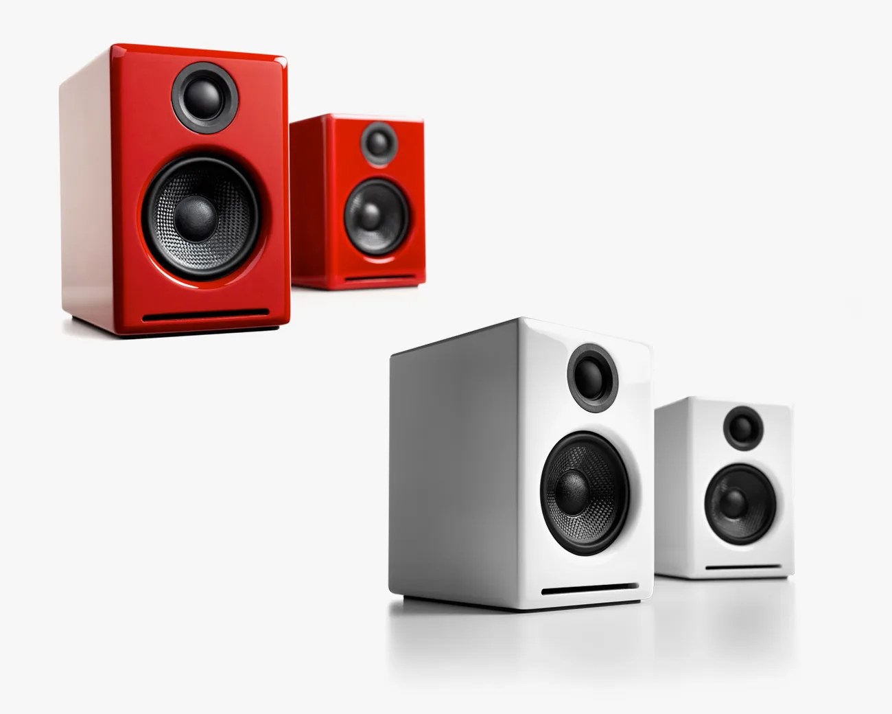 Two pairs of compact bookshelf speakers, one pair in glossy red and the other in glossy white, each with black speaker cones.