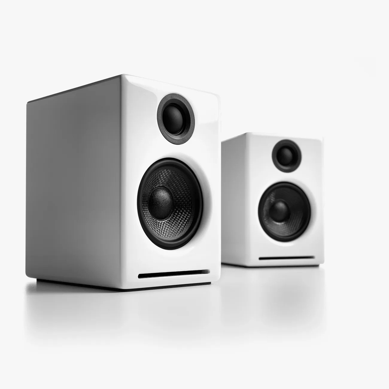 Pair of white rectangular bookshelf speakers with black drivers on a white surface.
