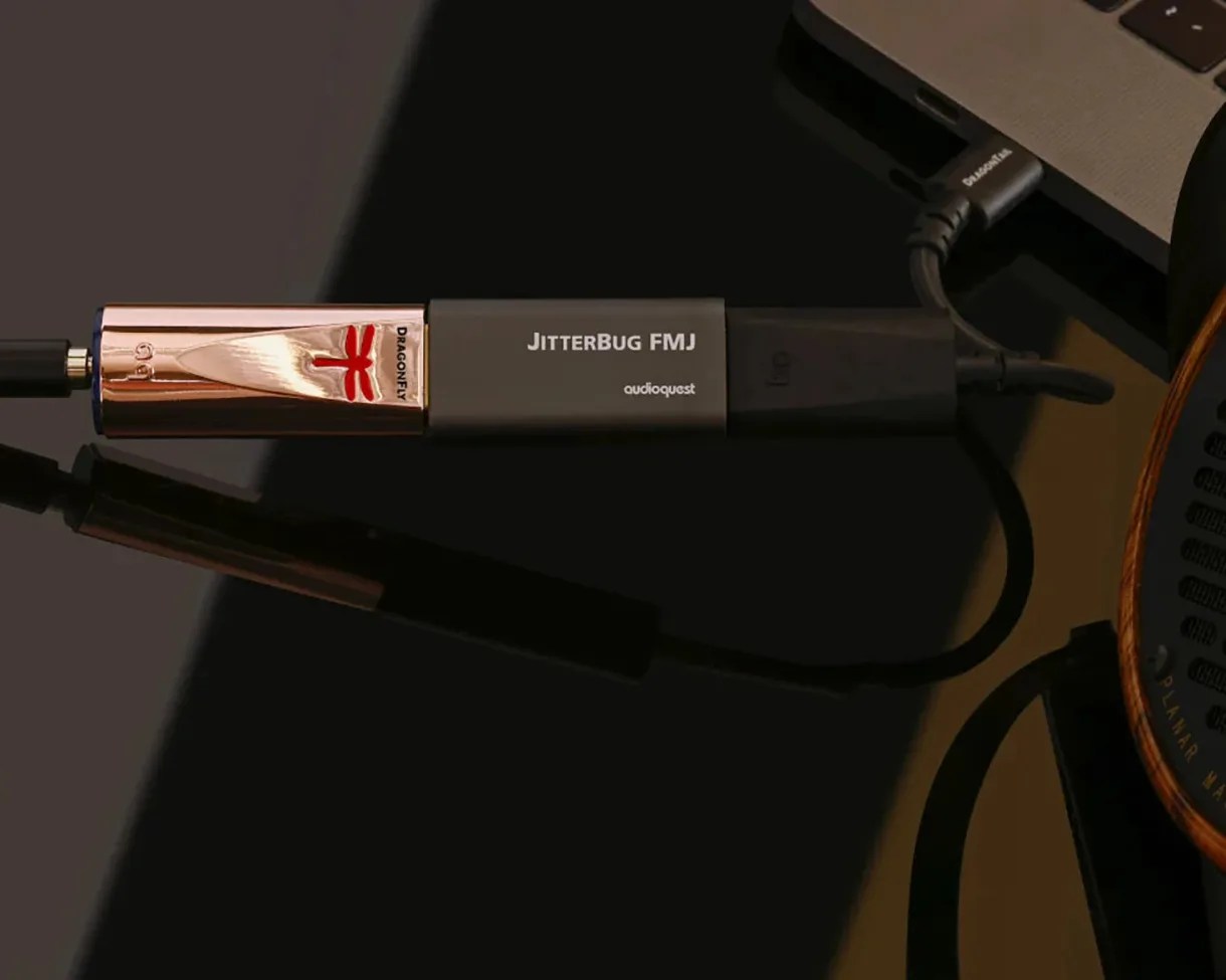 Black and copper AudioQuest JitterBug FMJ USB noise filter connected to a laptop and audio cable.