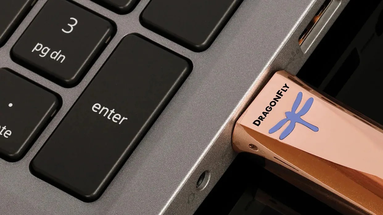 Rose gold Dragonfly USB flash drive plugged into a laptop next to the black Enter key.