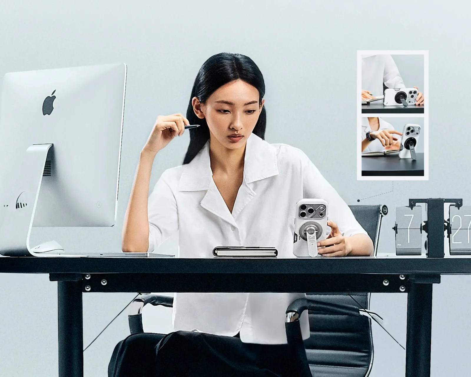 Person in a white shirt sitting at a desk with a white smartphone in a case featuring a circular metal stand.
