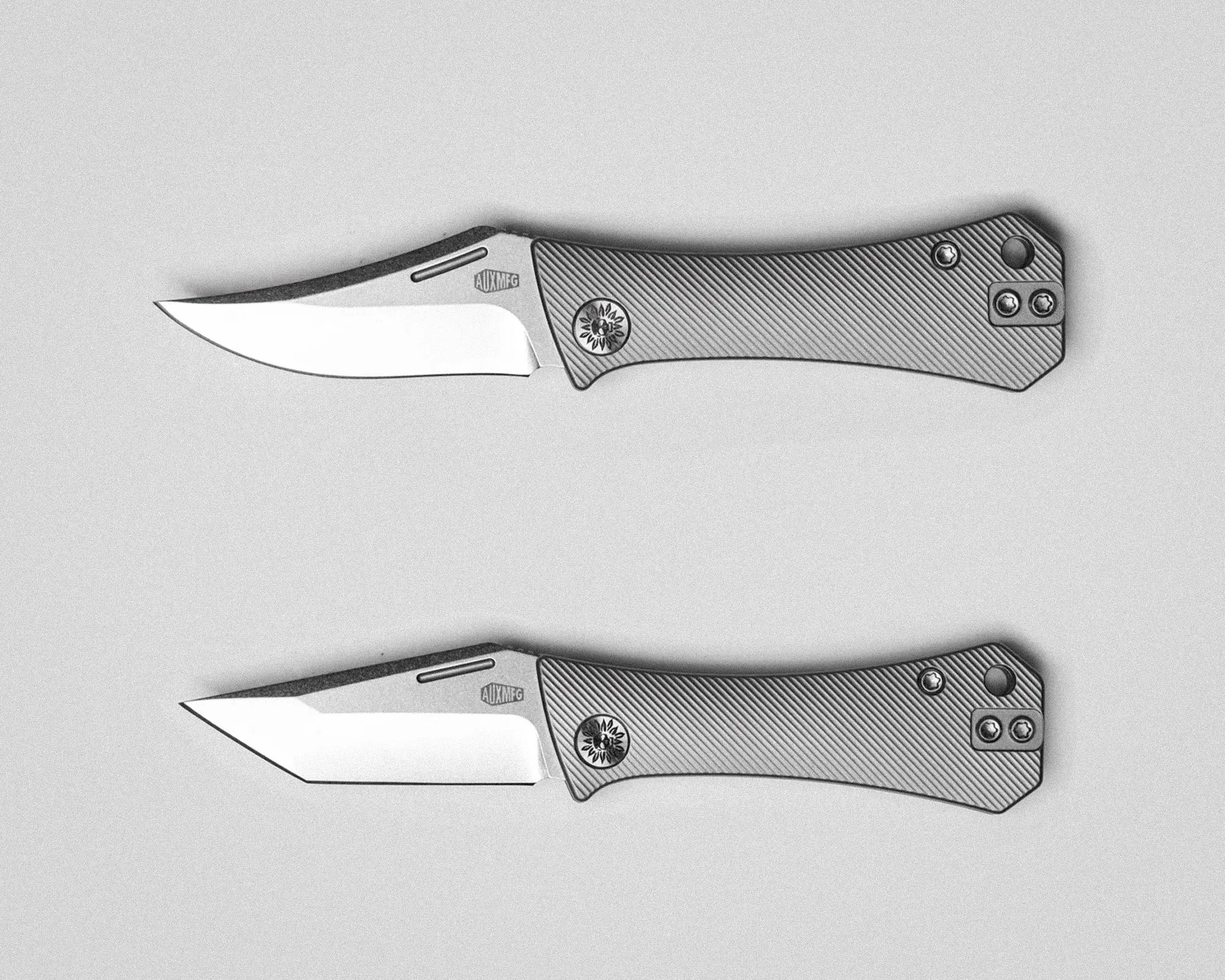 Two folding knives with textured handles and stainless steel blades on a light surface.