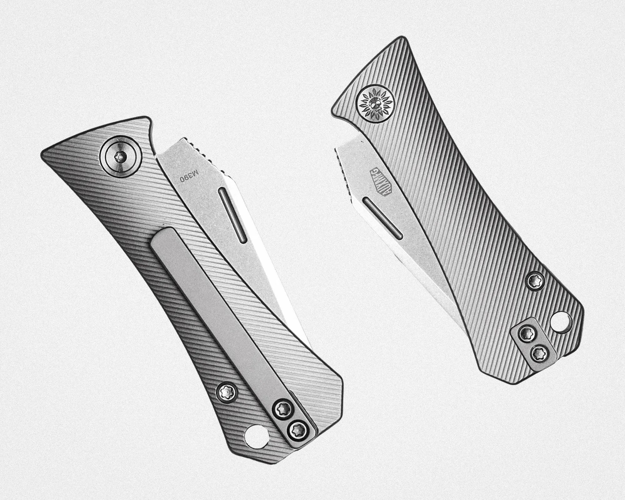 Two partially open folding knives with textured metal handles and visible screws on a white background.