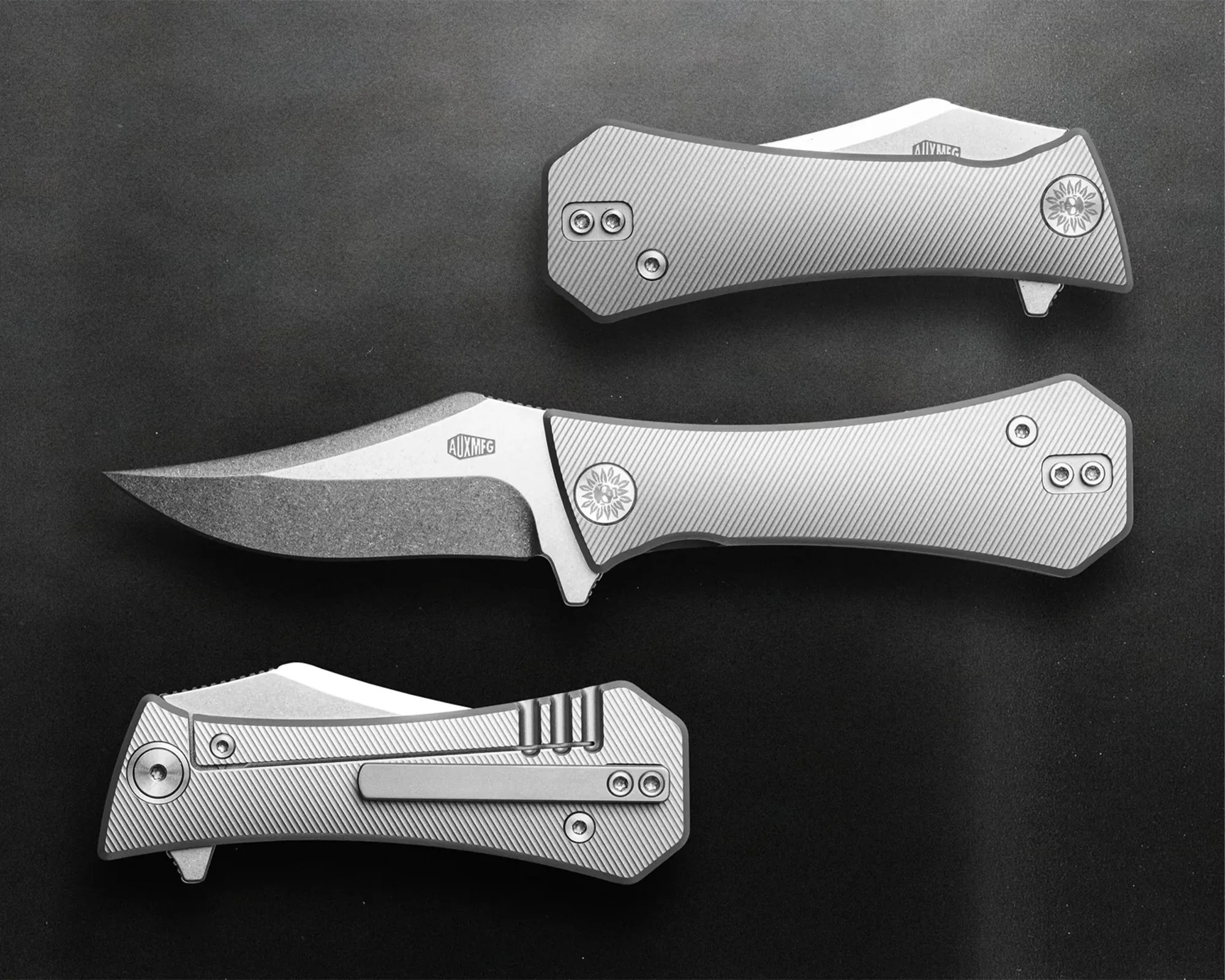 Three silver folding knives with textured handles and visible screws on a dark surface.
