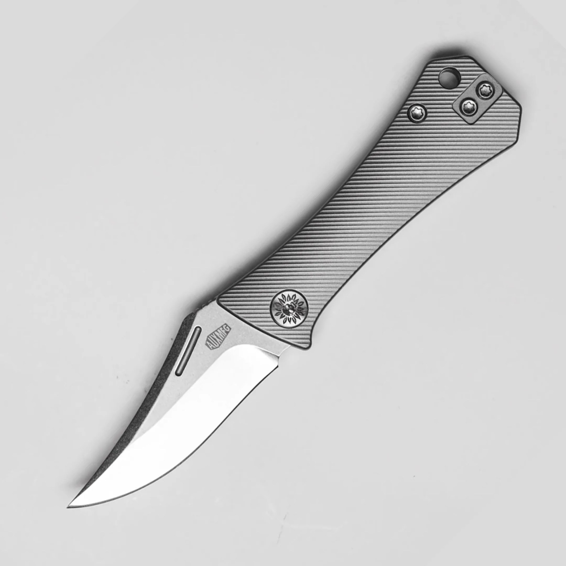 Silver folding knife with a textured gray handle and a curved blade on a light background.