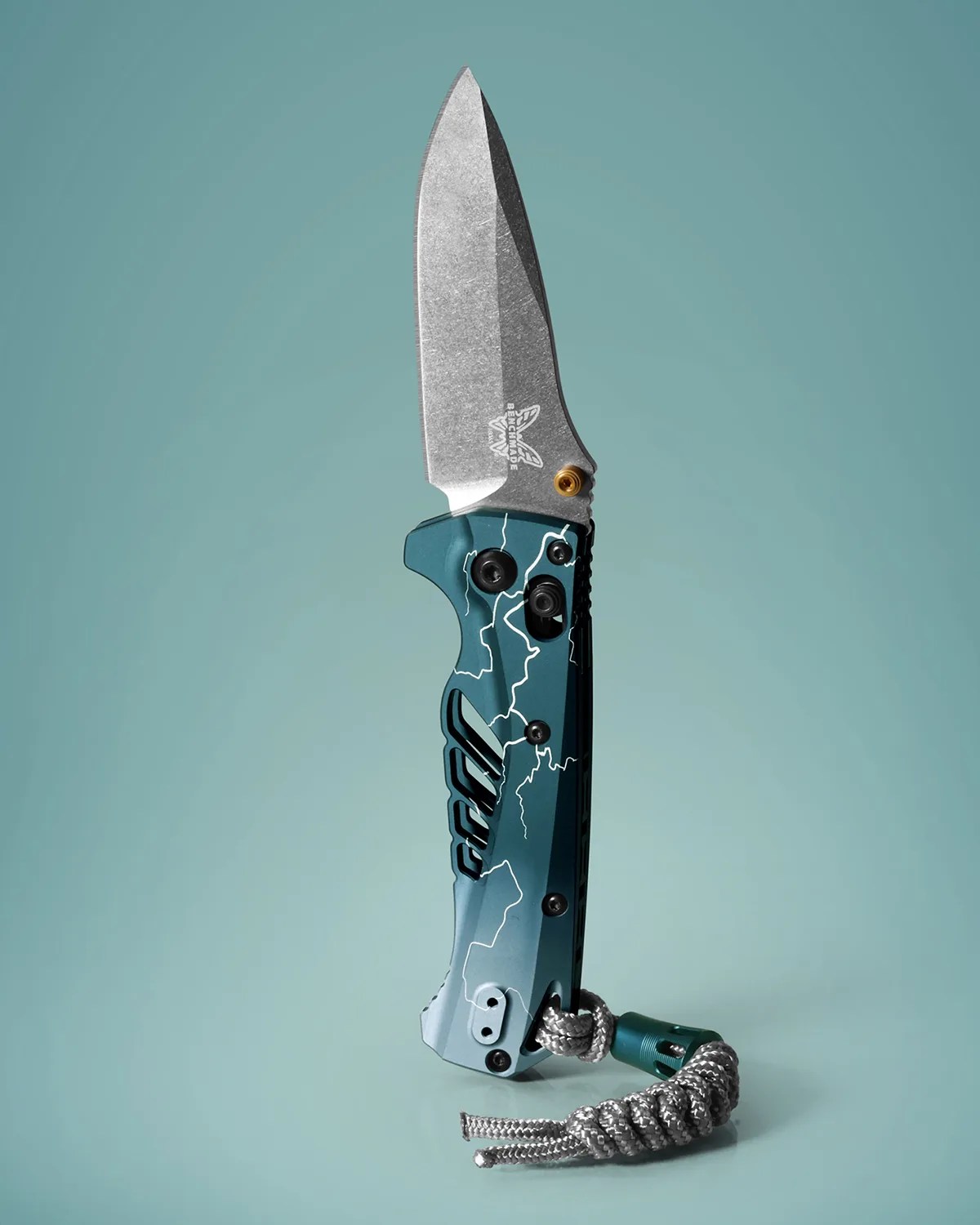 Folding knife with stonewashed blade and blue handle featuring white lightning pattern and attached silver paracord.