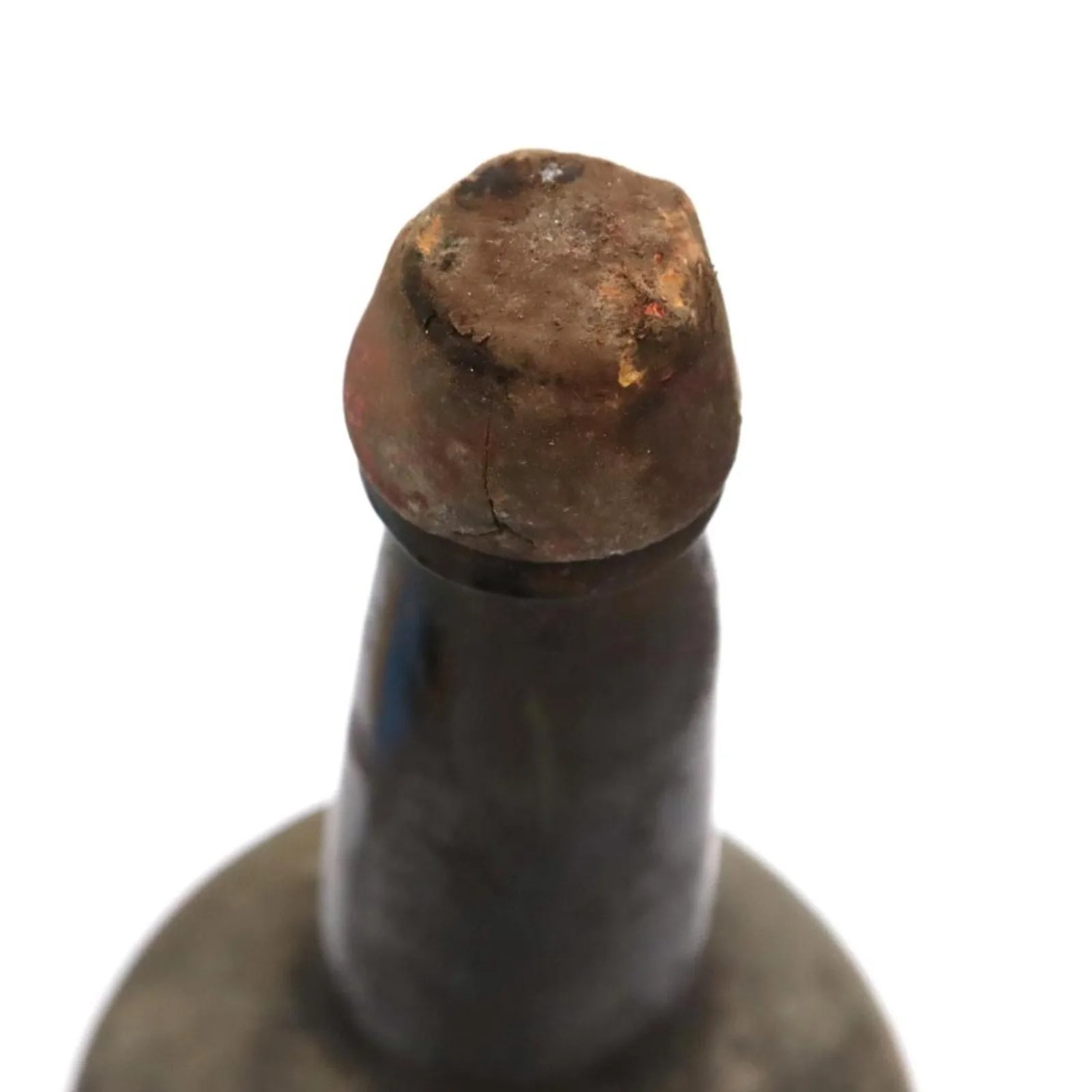 Close-up of a dusty, aged cork sealing the top of a dark glass bottle.