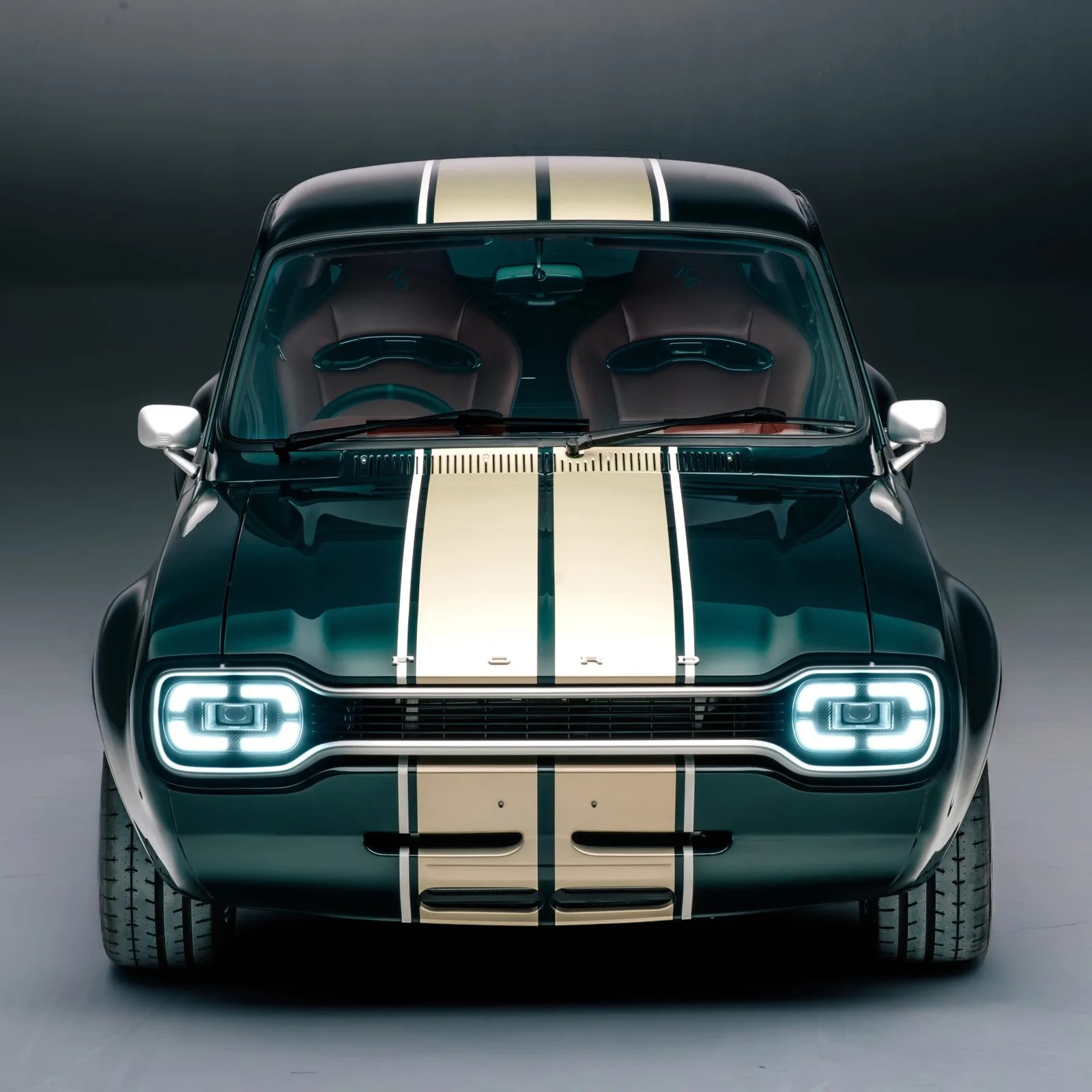 Front view of a black vintage Ford car with cream racing stripes and illuminated square headlights.