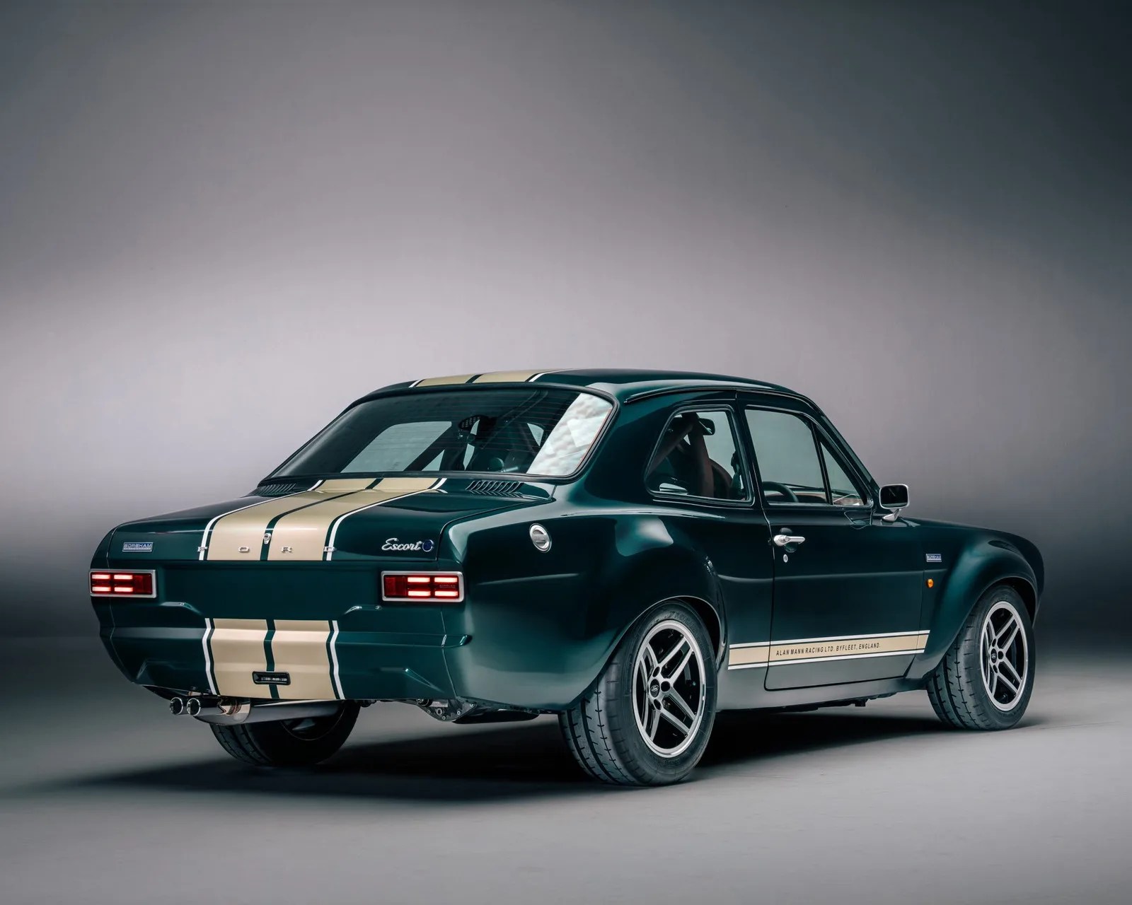 Dark green Ford Escort with beige racing stripes and sporty alloy wheels in a studio setting.