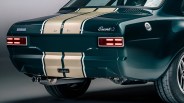 Rear view of a dark green Ford Escort with beige racing stripes and dual exhaust pipes.