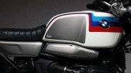 White BMW motorcycle fuel tank with blue and red stripes and black leather seat.