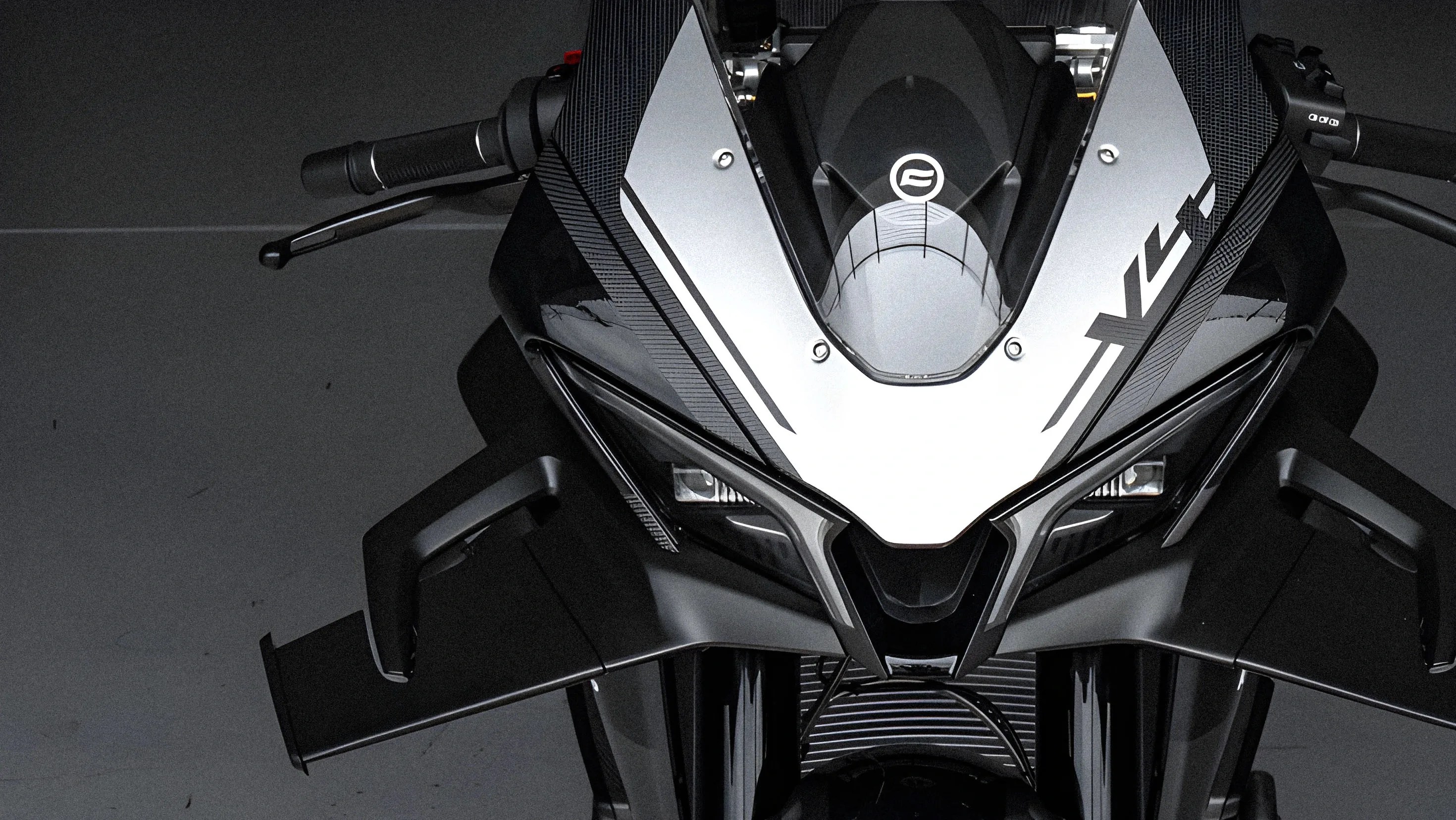 Front view of a black and silver sport motorcycle with angular design and aerodynamic winglets.