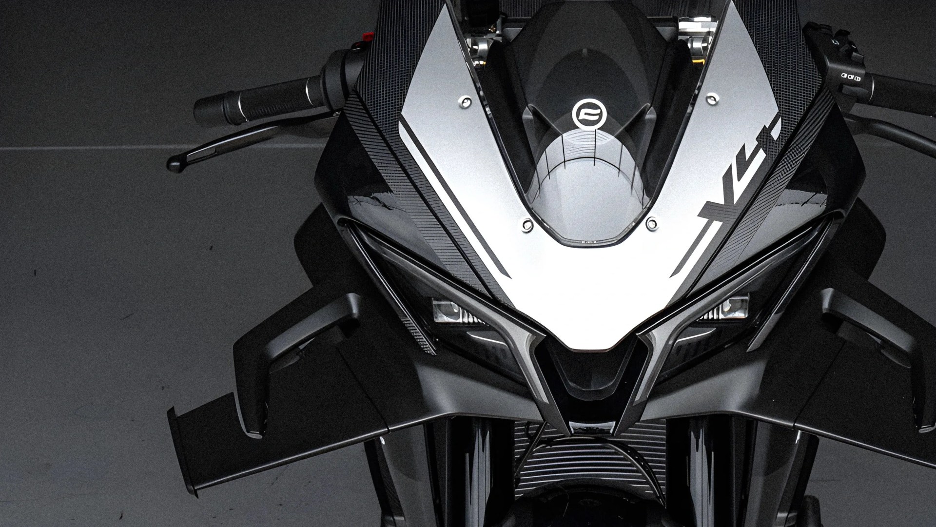 Front view of a black and silver sport motorcycle with angular design and aerodynamic winglets.