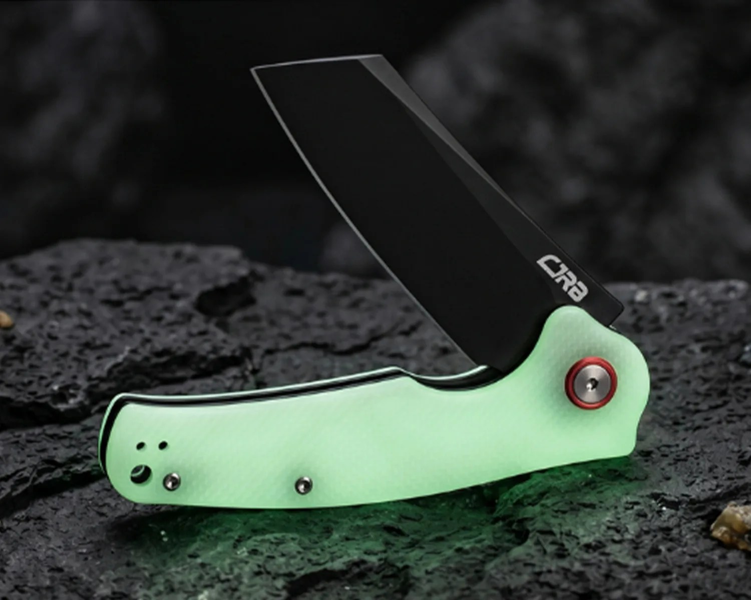 Folding knife with a black blade and mint green textured handle resting on dark textured rock.