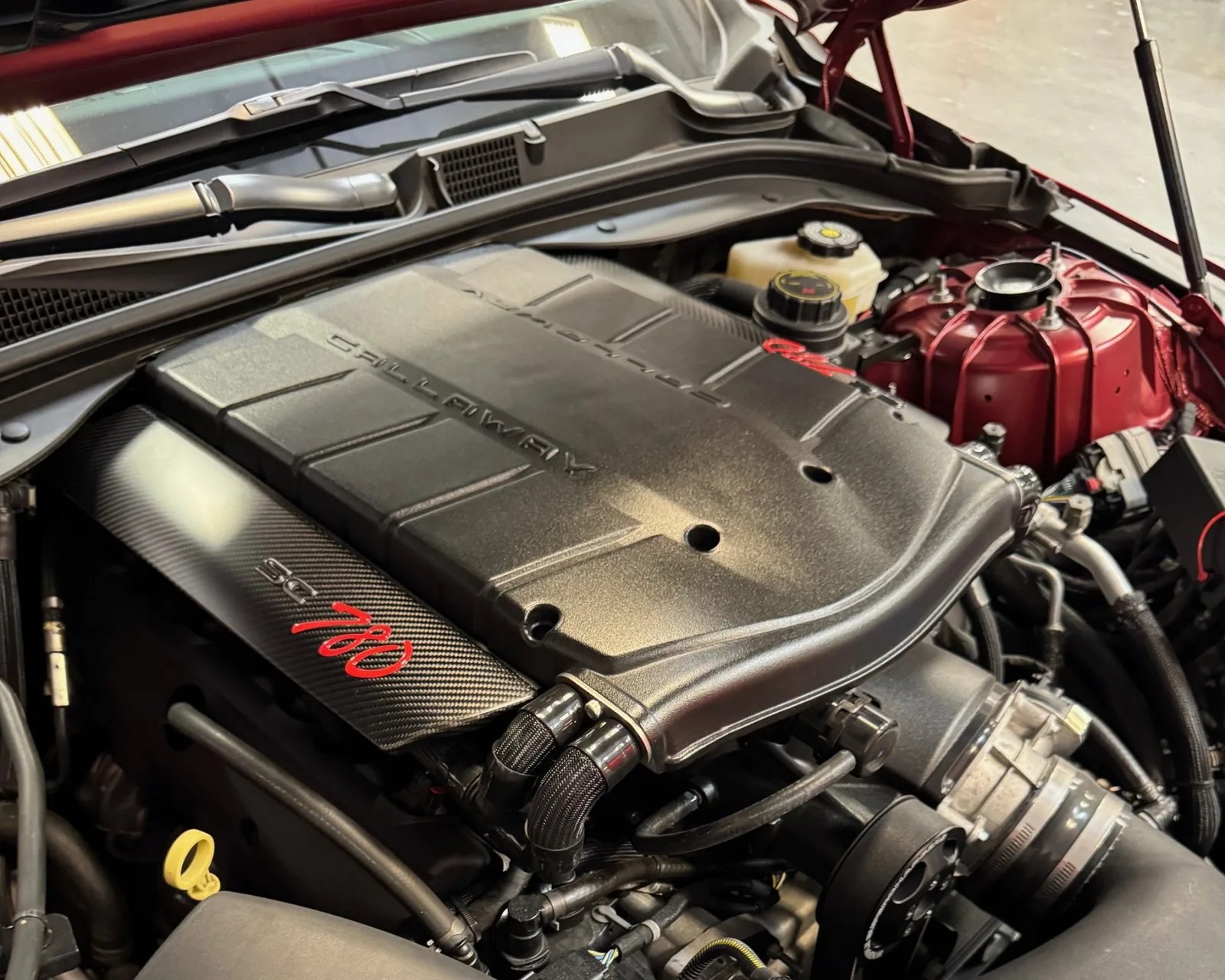 Close-up of a Callaway SC780 engine cover with black and red detailing inside a car engine bay.