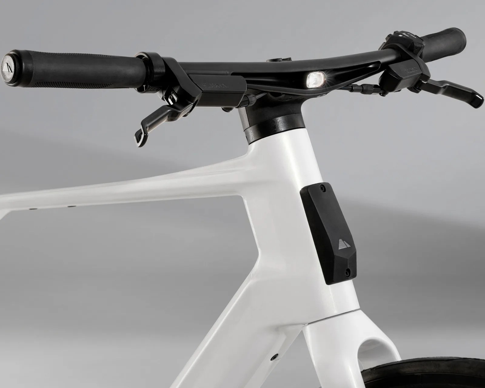 Close-up of white bicycle frame with integrated black handlebar and front light on a gray background.