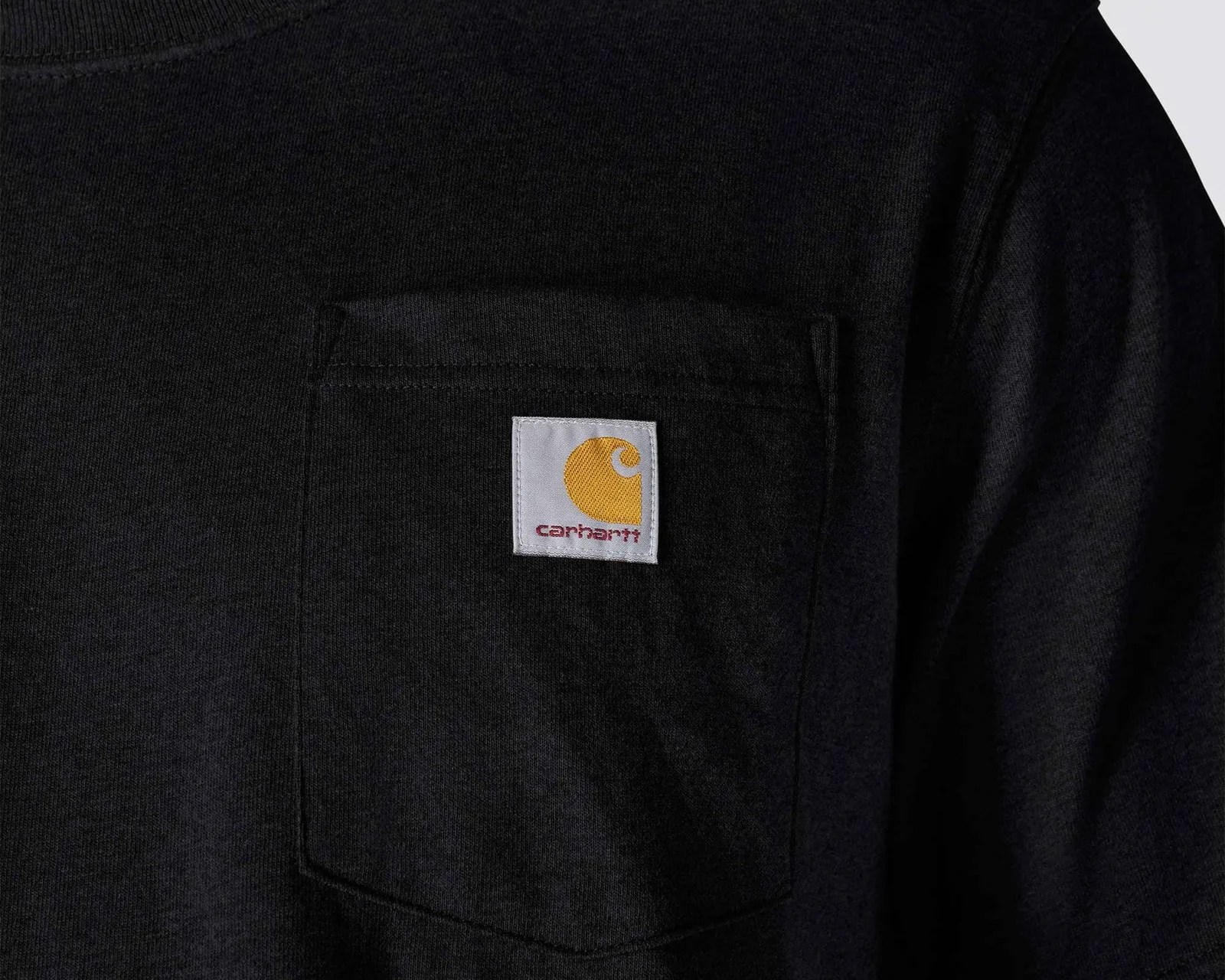 Close-up of a black Carhartt shirt pocket with a white and yellow Carhartt logo patch.