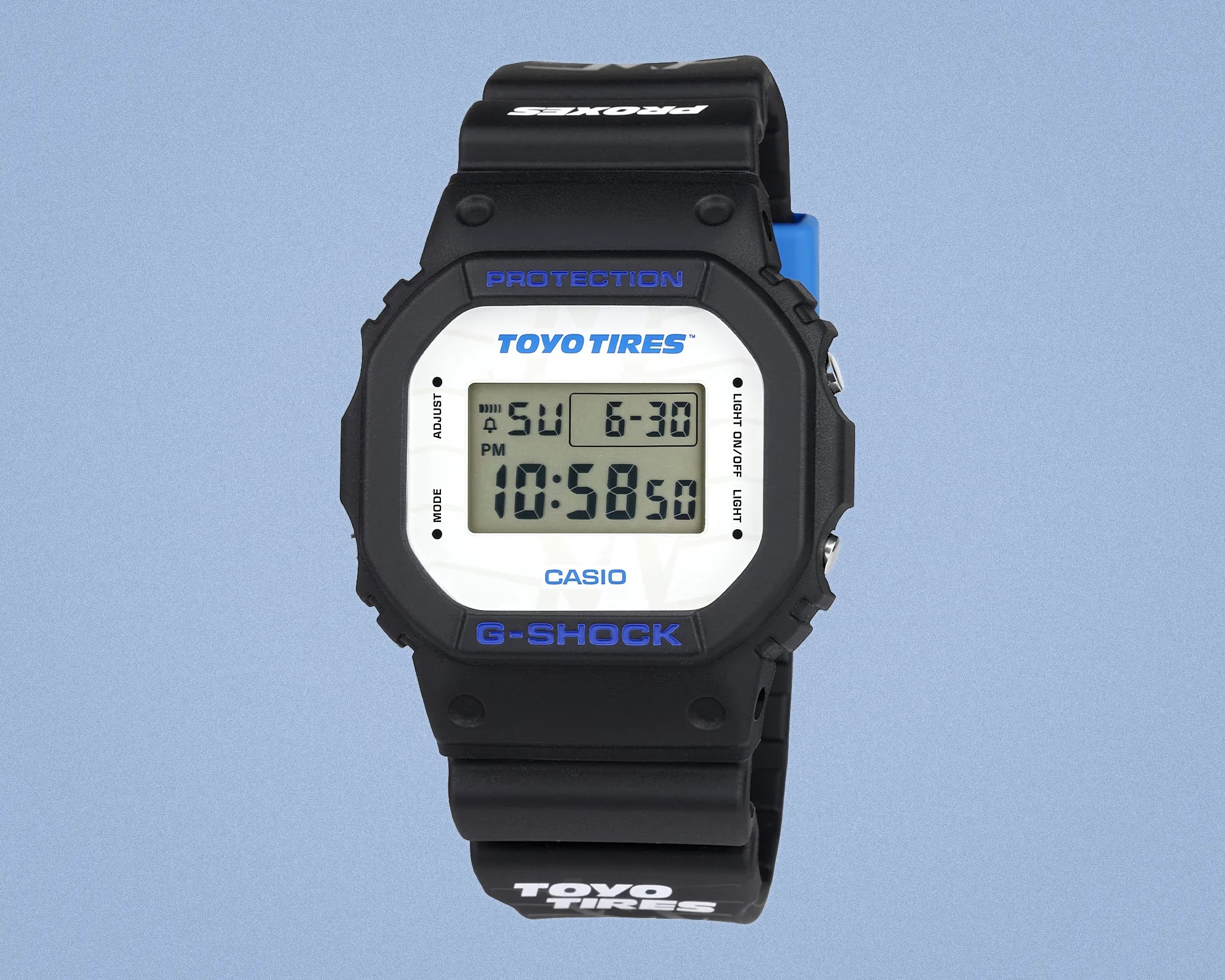 Black Casio G-Shock digital watch with white face and blue "TOYO TIRES" and "G-SHOCK" branding on the bezel and strap.