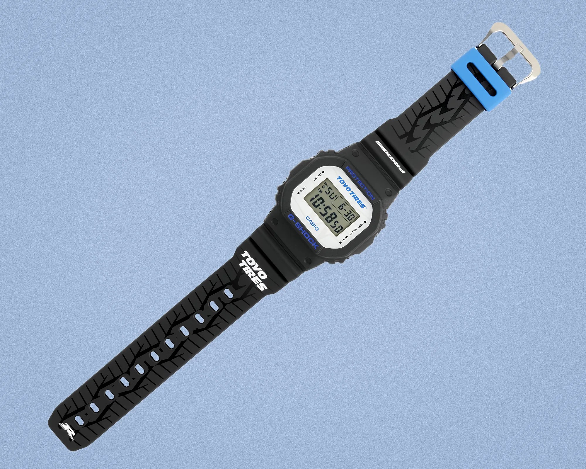 Black Casio G-Shock digital watch with tire tread patterned strap and blue buckle on a blue background.