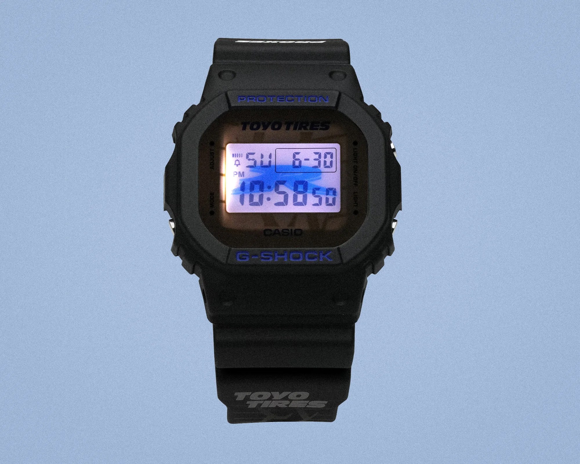 Black Casio G-Shock digital watch with blue backlight and Toyo Tires logo on strap and face.