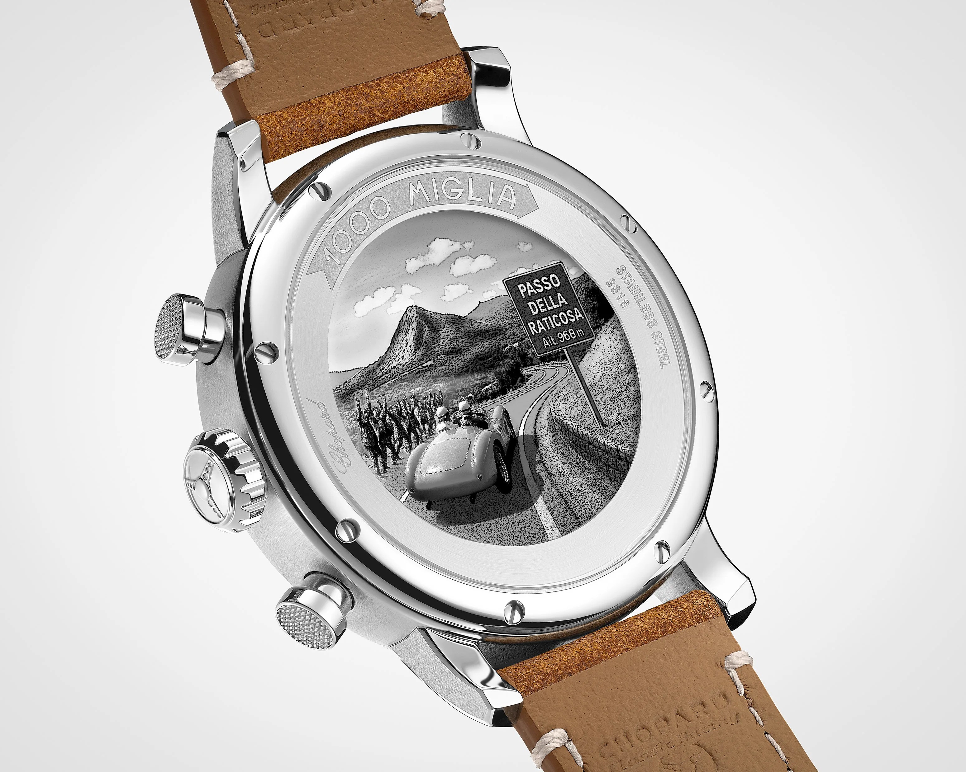 Close-up of a stainless steel watch back with engraved vintage car and road scene, brown leather strap.