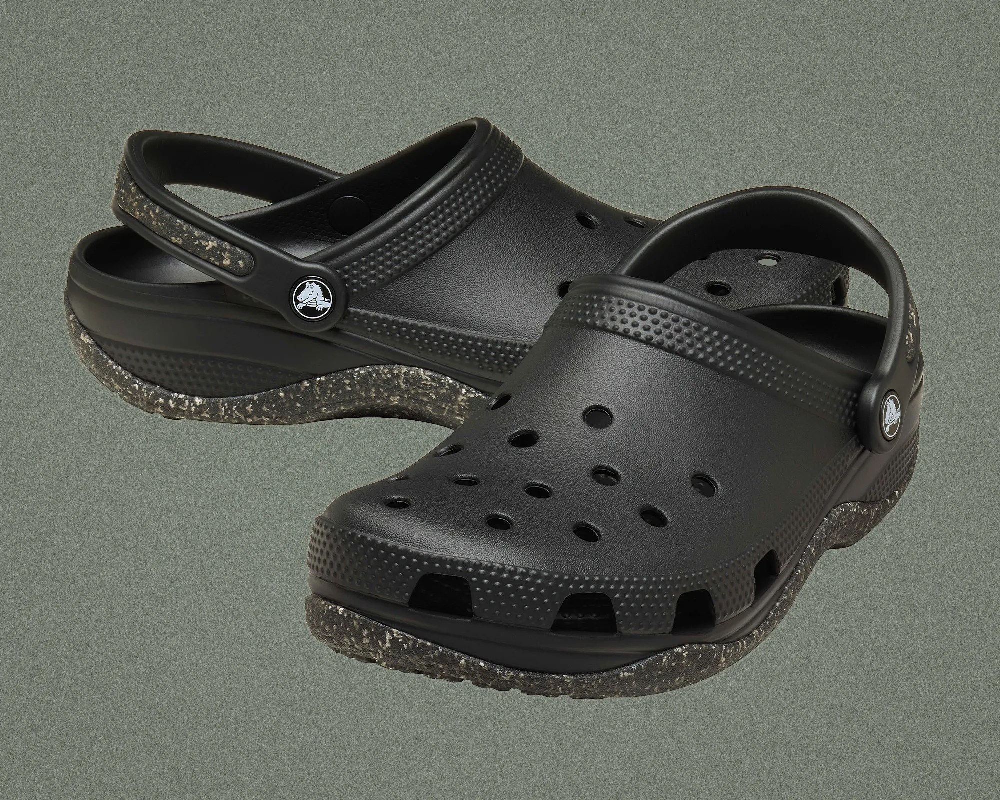 Pair of black Crocs clogs with speckled textured soles and adjustable heel straps.