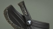 Close-up of black Crocs shoe with speckled sole and textured strap featuring a circular logo with a crocodile.