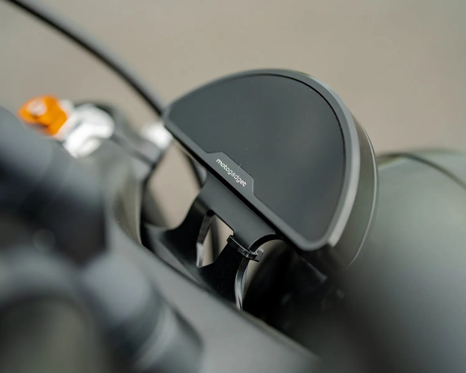 Black MotoGadget digital motorcycle dashboard mounted on a bike handlebar.