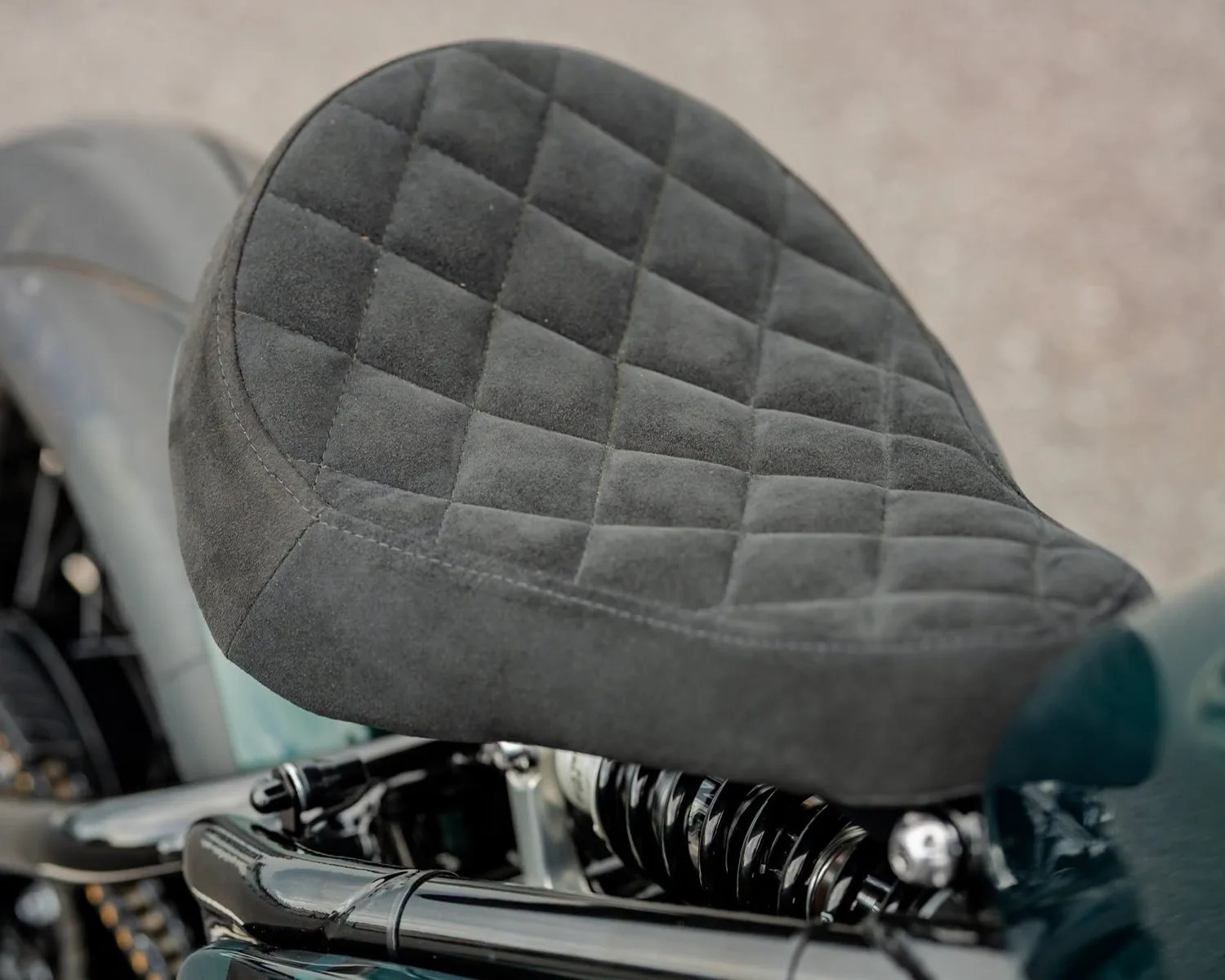 Black quilted suede motorcycle seat with visible suspension springs underneath.