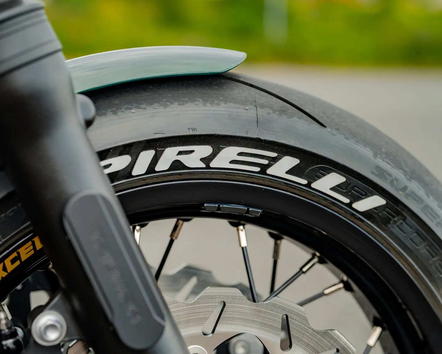 Close-up of a Pirelli motorcycle tire mounted on a black spoked wheel with a disc brake rotor.