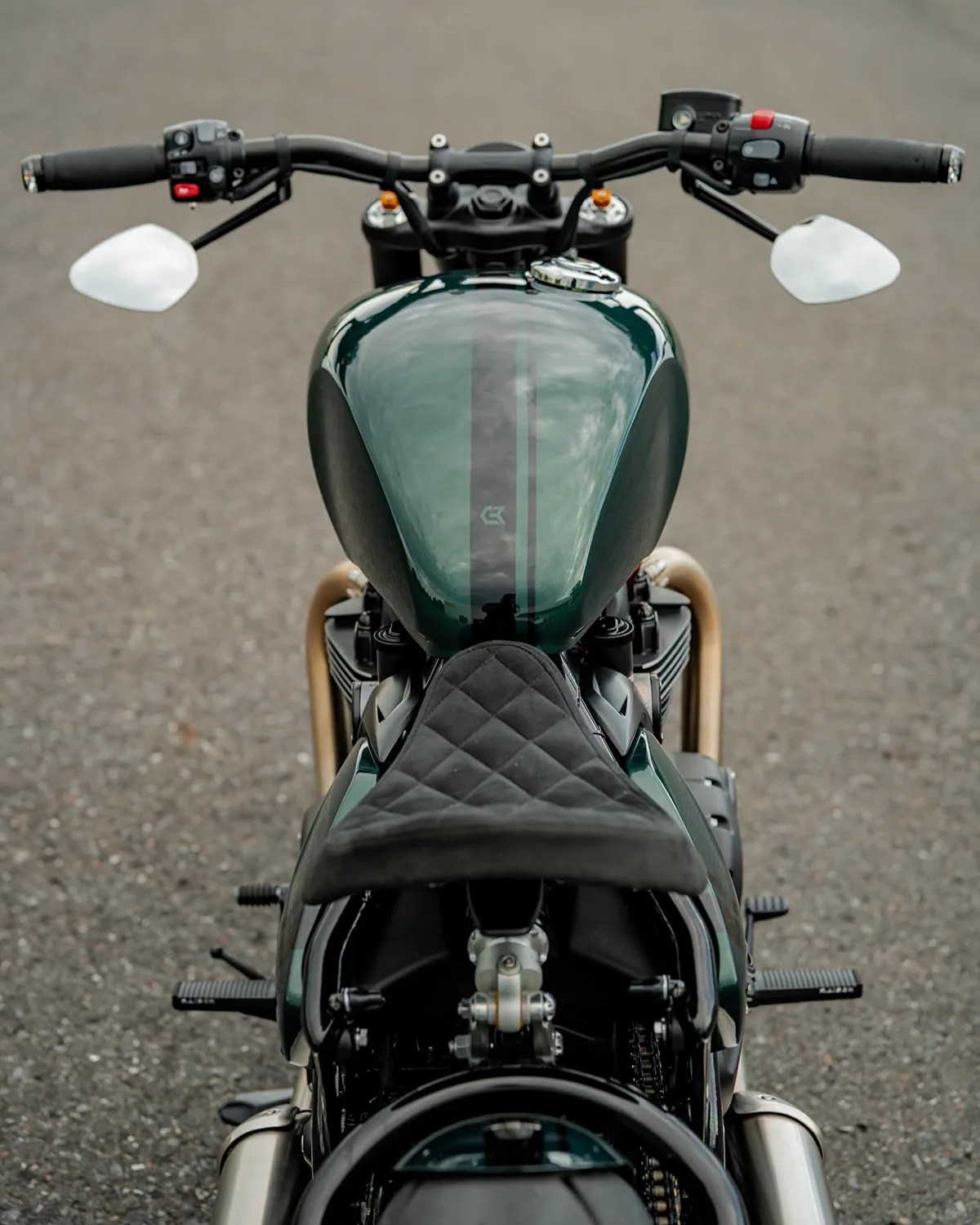 Dark green motorcycle fuel tank with black racing stripes and a quilted black seat viewed from above.