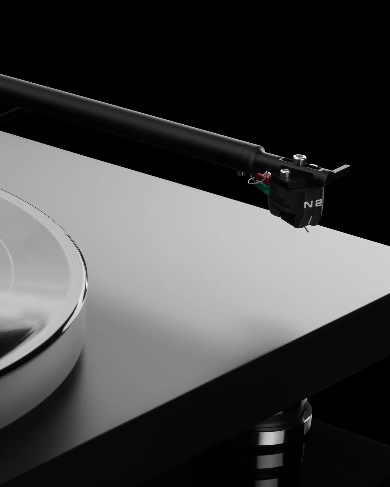 Close-up of a black tonearm and cartridge labeled "N2" on a silver turntable platter.