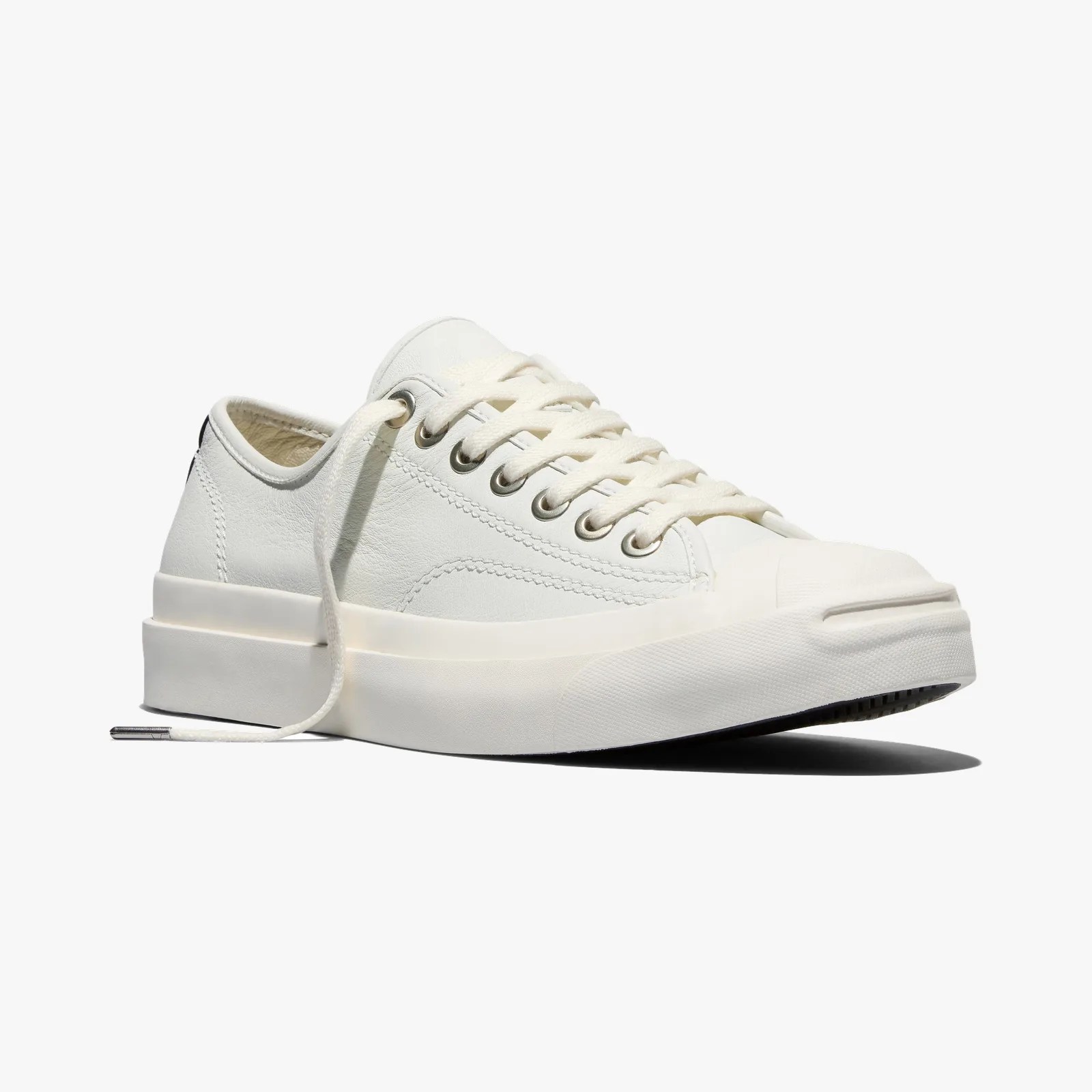 Off-white low-top sneaker with thick rubber sole and metal eyelets, laces untied.