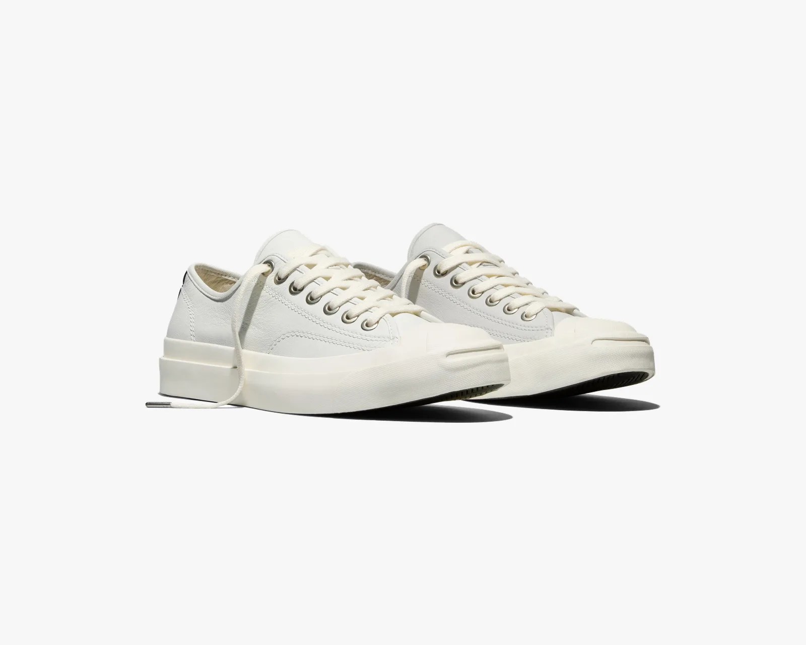 Pair of off-white low-top sneakers with thick rubber soles and metal eyelets on a white background.