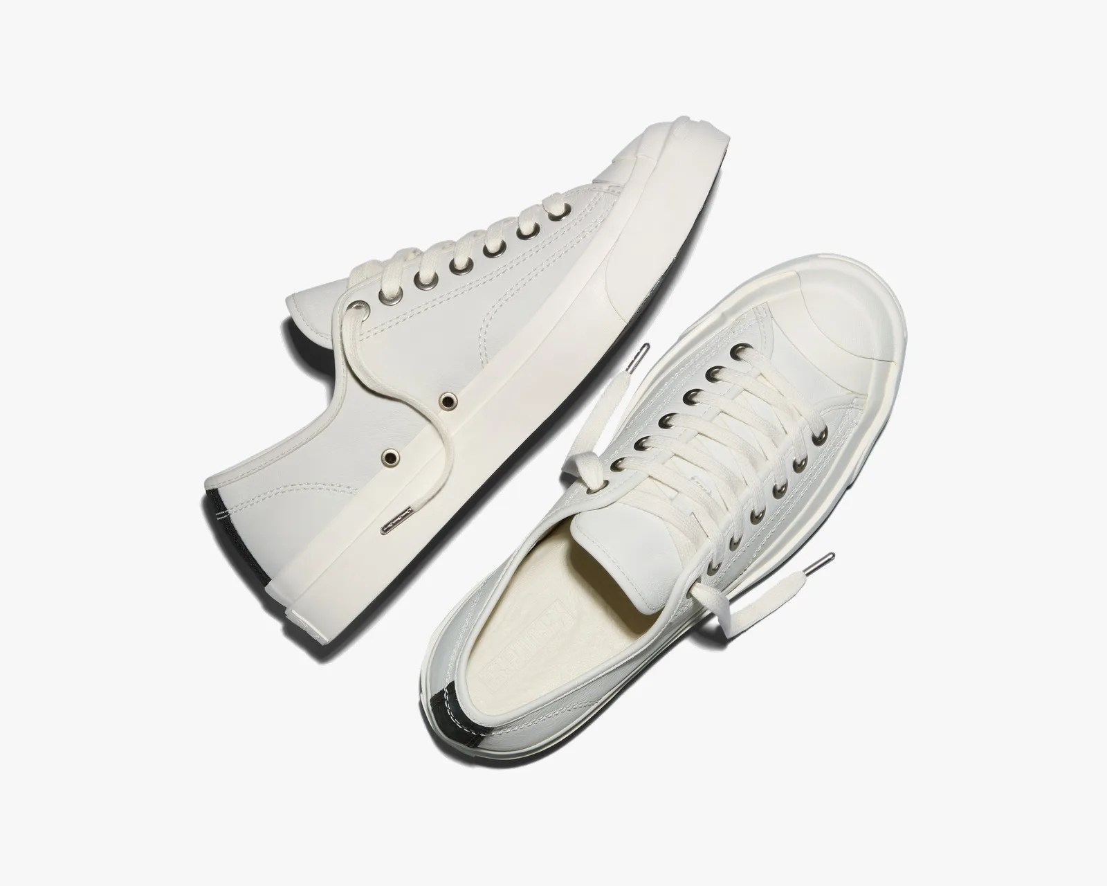 Pair of white low-top sneakers with white laces and black heel tabs on a white background.