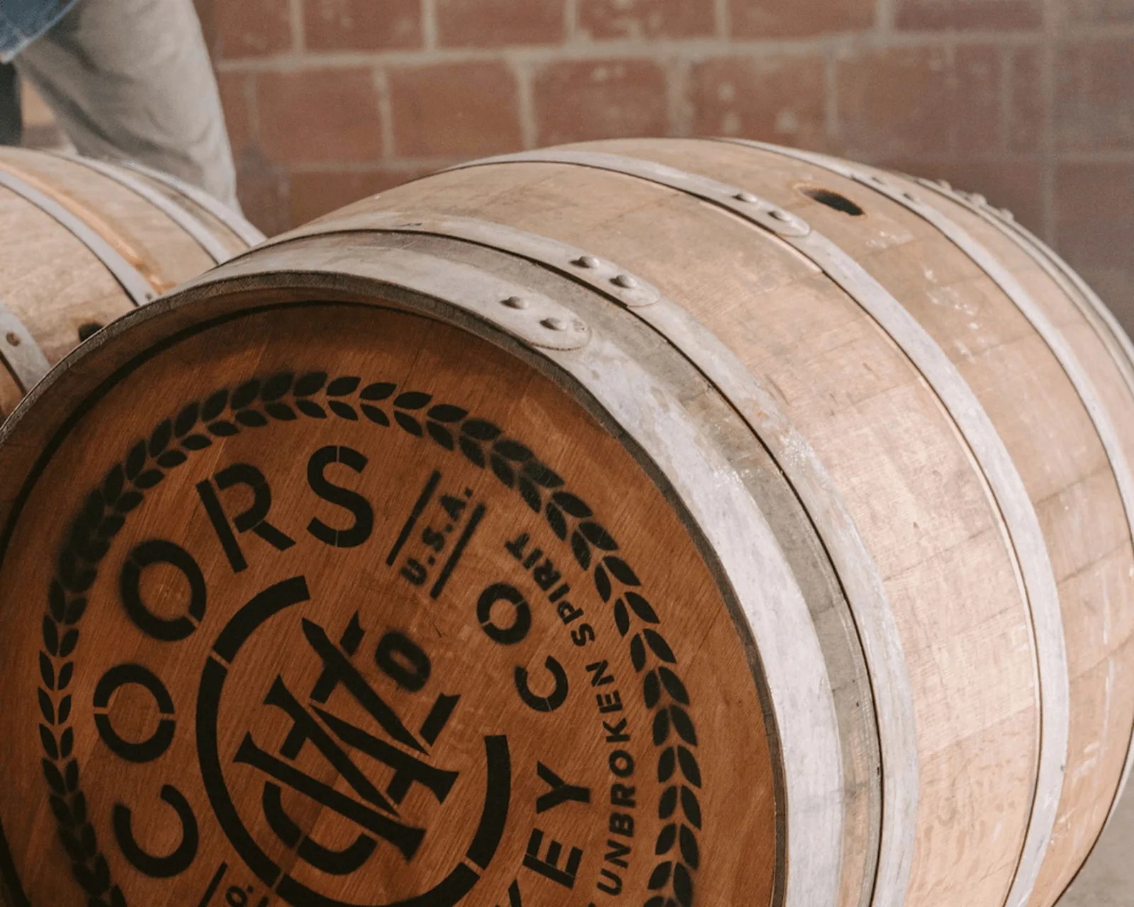 Wooden whiskey barrel with metal bands and black printed text on the barrel head.