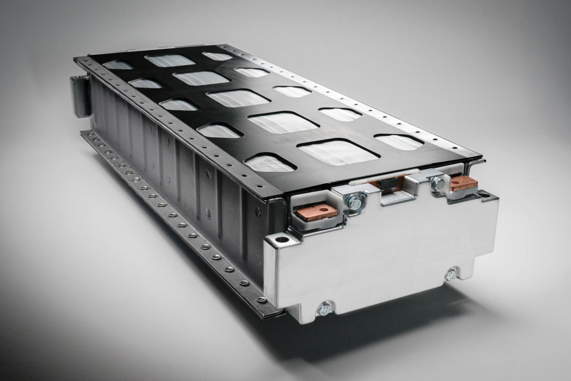 Rectangular silver and black metal battery pack with copper terminals on a gray background.