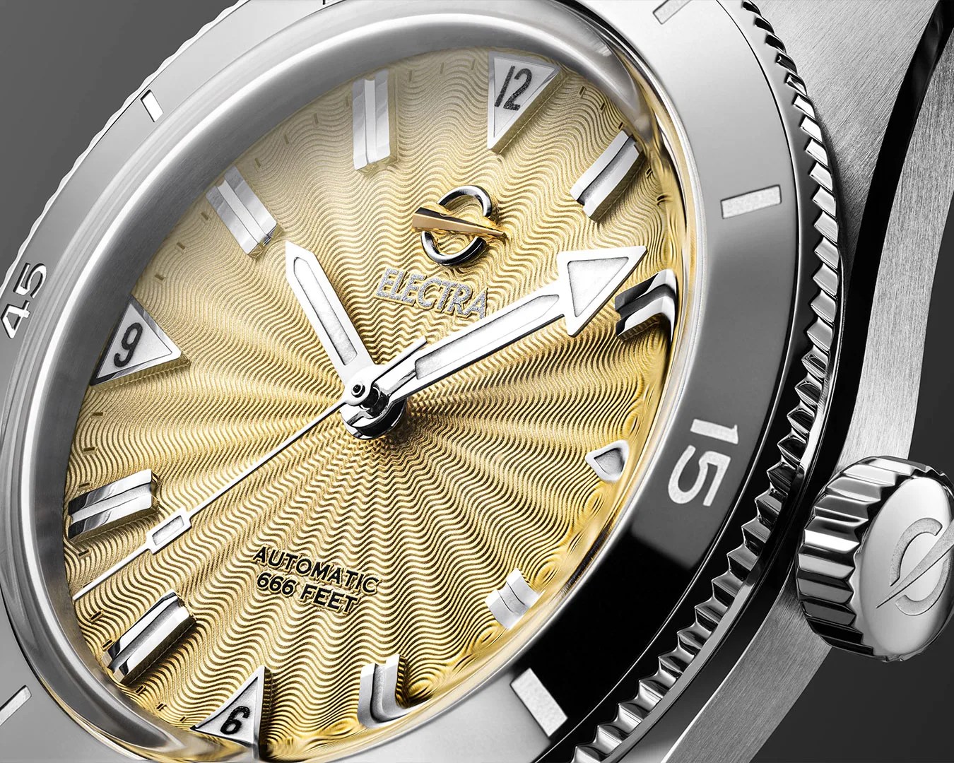 Close-up of a silver watch with a textured gold dial, silver hands, and markers, labeled "ELEGRA" and "AUTOMATIC 666 FEET.
