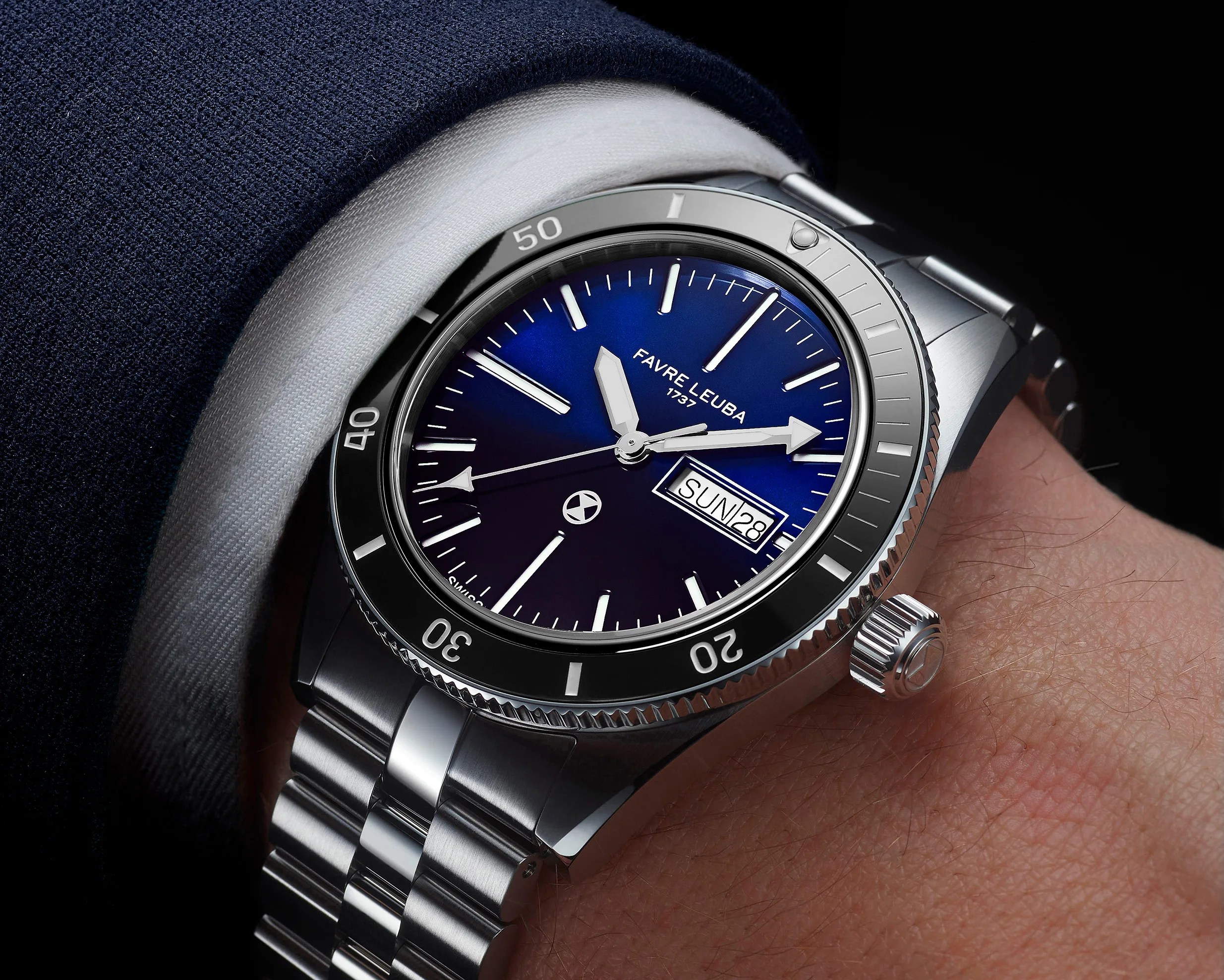 Silver metal wristwatch with blue dial, white markers, date display, and rotating bezel on a wrist.
