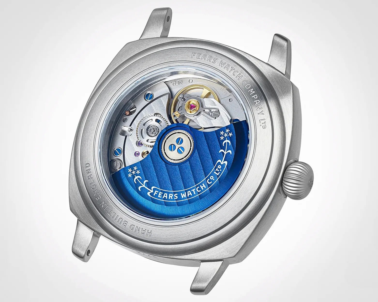 Silver watch case back showing mechanical movement with blue rotor engraved "Fears Watch Co. Ltd" and "Hand Built in England" text.