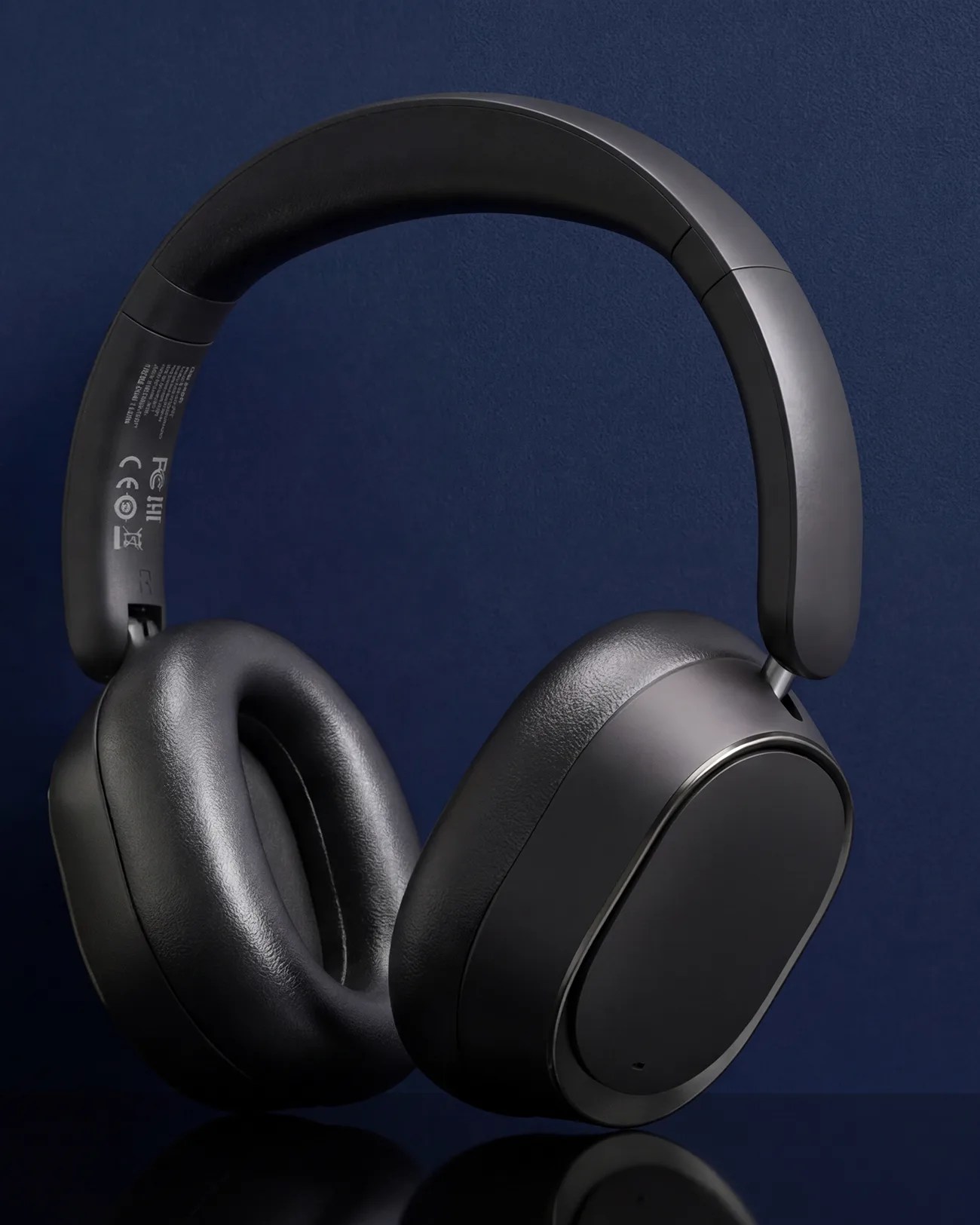 Black over-ear wireless headphones with padded ear cushions and a matte finish on a dark blue background.