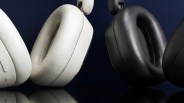 Close-up of white and black over-ear headphone ear cushions against a dark background.