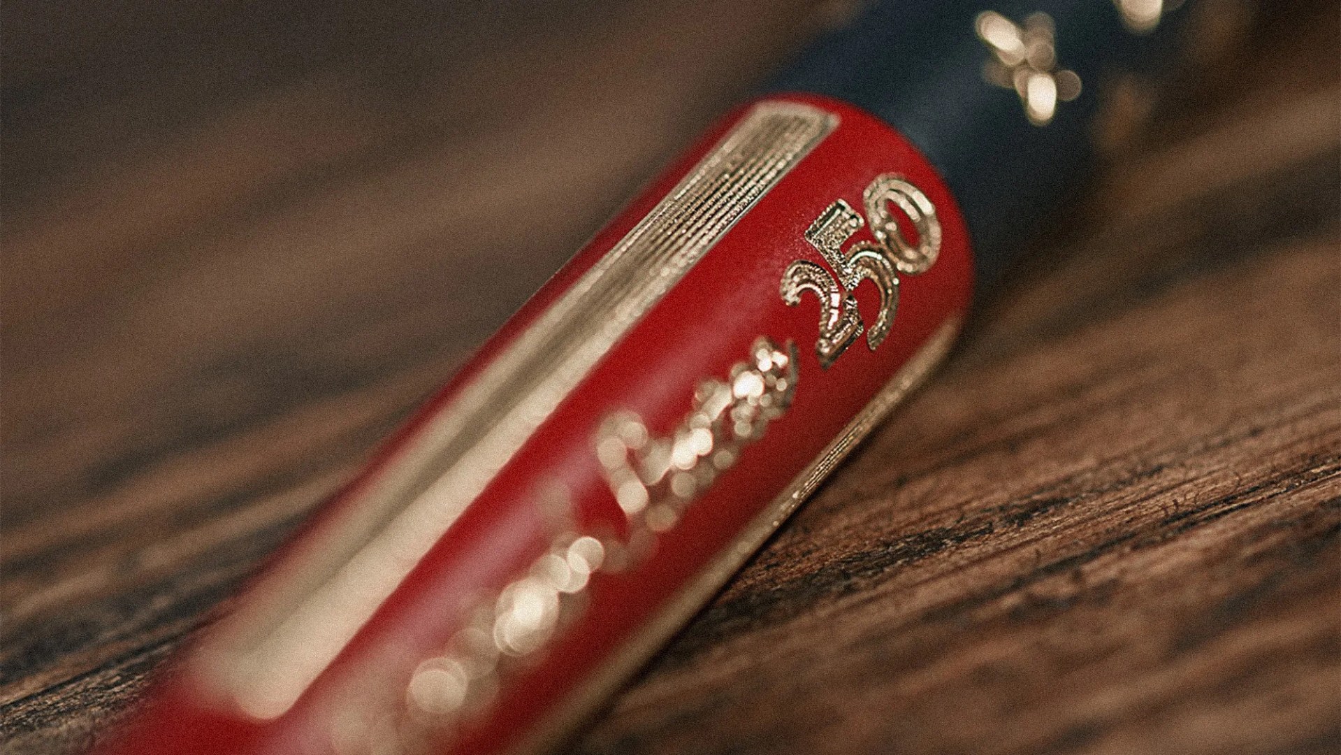 Close-up of a red and blue pen with gold embossed text "250" on a wooden surface.
