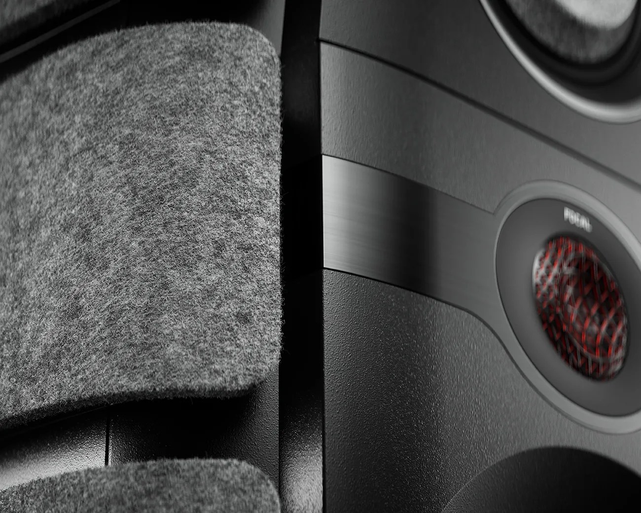 Close-up of a black speaker with textured fabric covering and a red-accented tweeter.