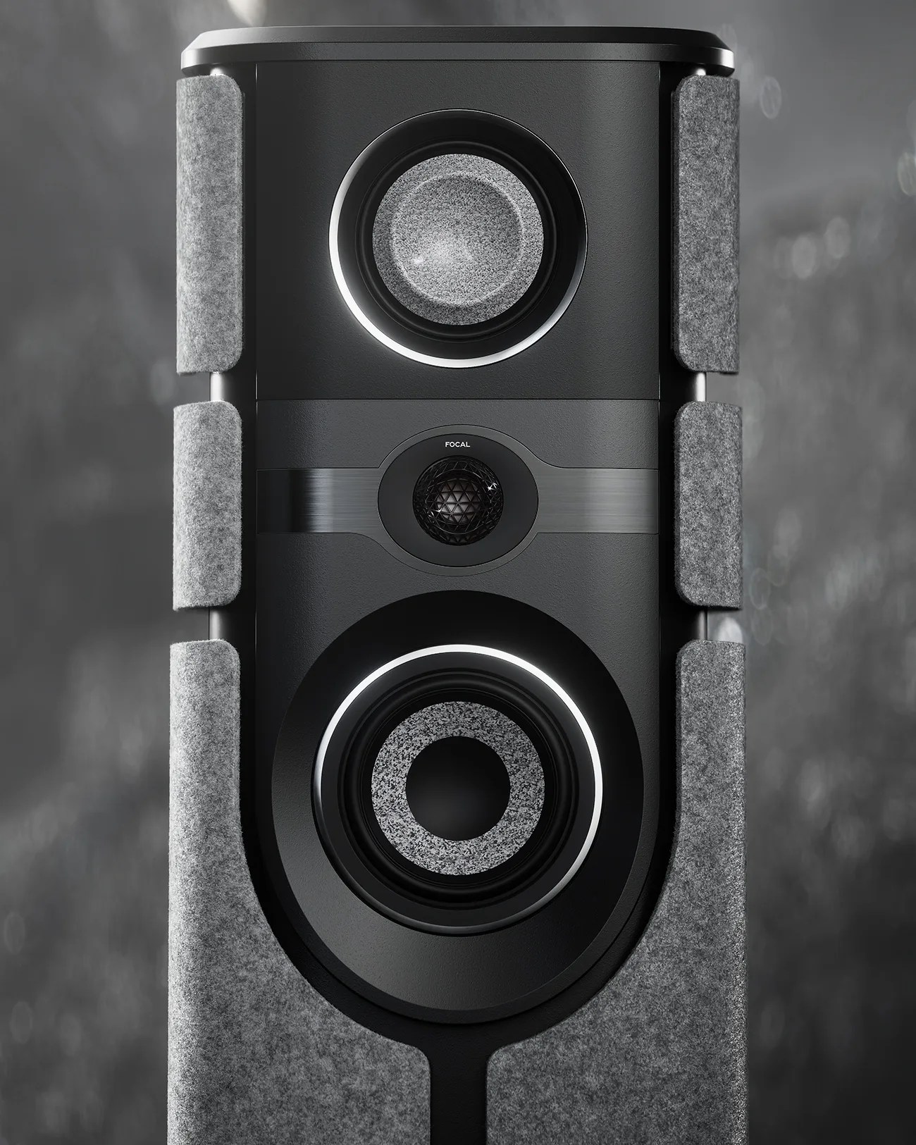 Close-up of a black Focal speaker with two large drivers and a central tweeter, partially covered by gray felt panels.
