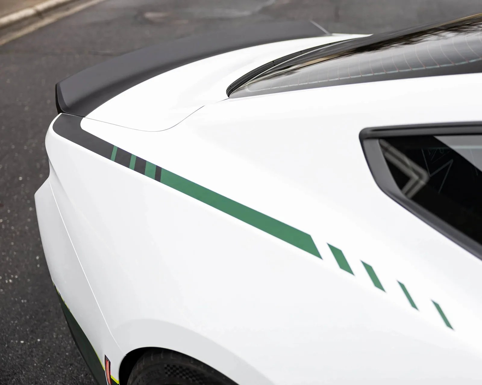 White car rear quarter panel with green and black racing stripes and a black rear spoiler.