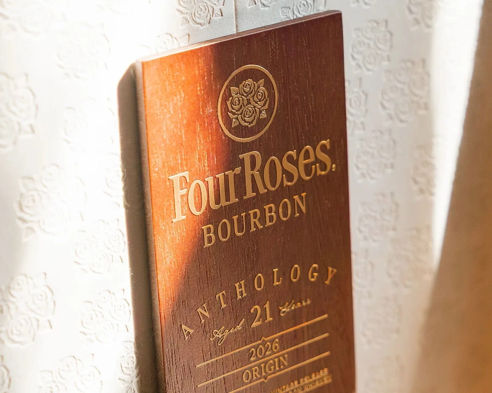 Close-up of a wooden Four Roses Bourbon plaque with gold lettering and a rose emblem.