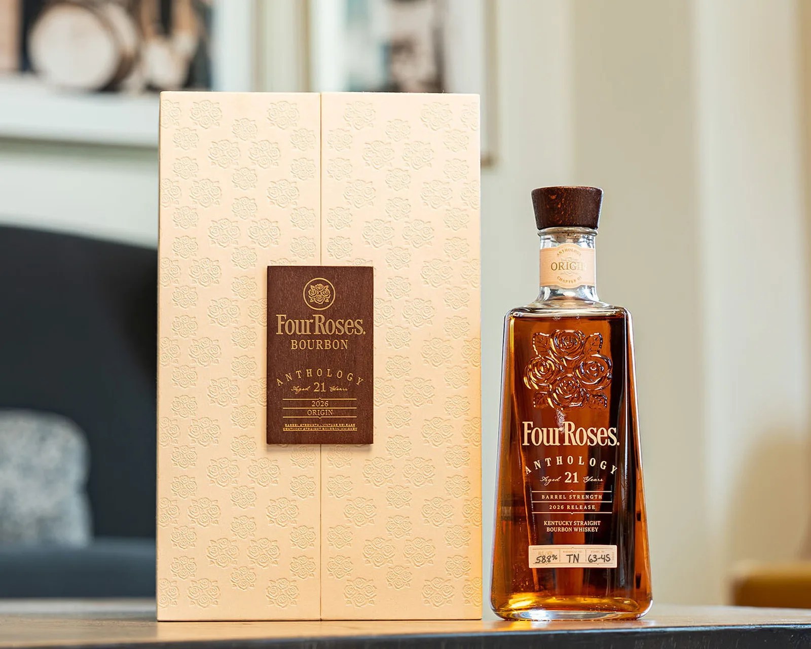 Four Roses Anthology 21-year-old bourbon bottle with wooden cap next to beige embossed box on a table.