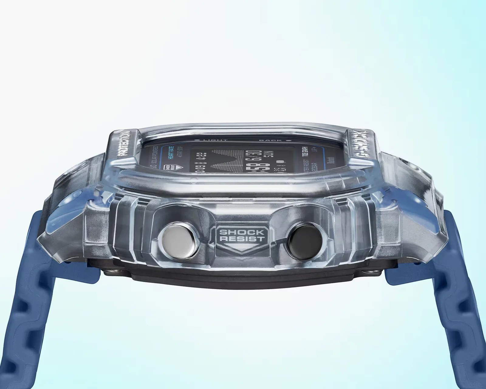 Transparent gray digital watch case with "Shock Resist" label and blue strap ends visible.