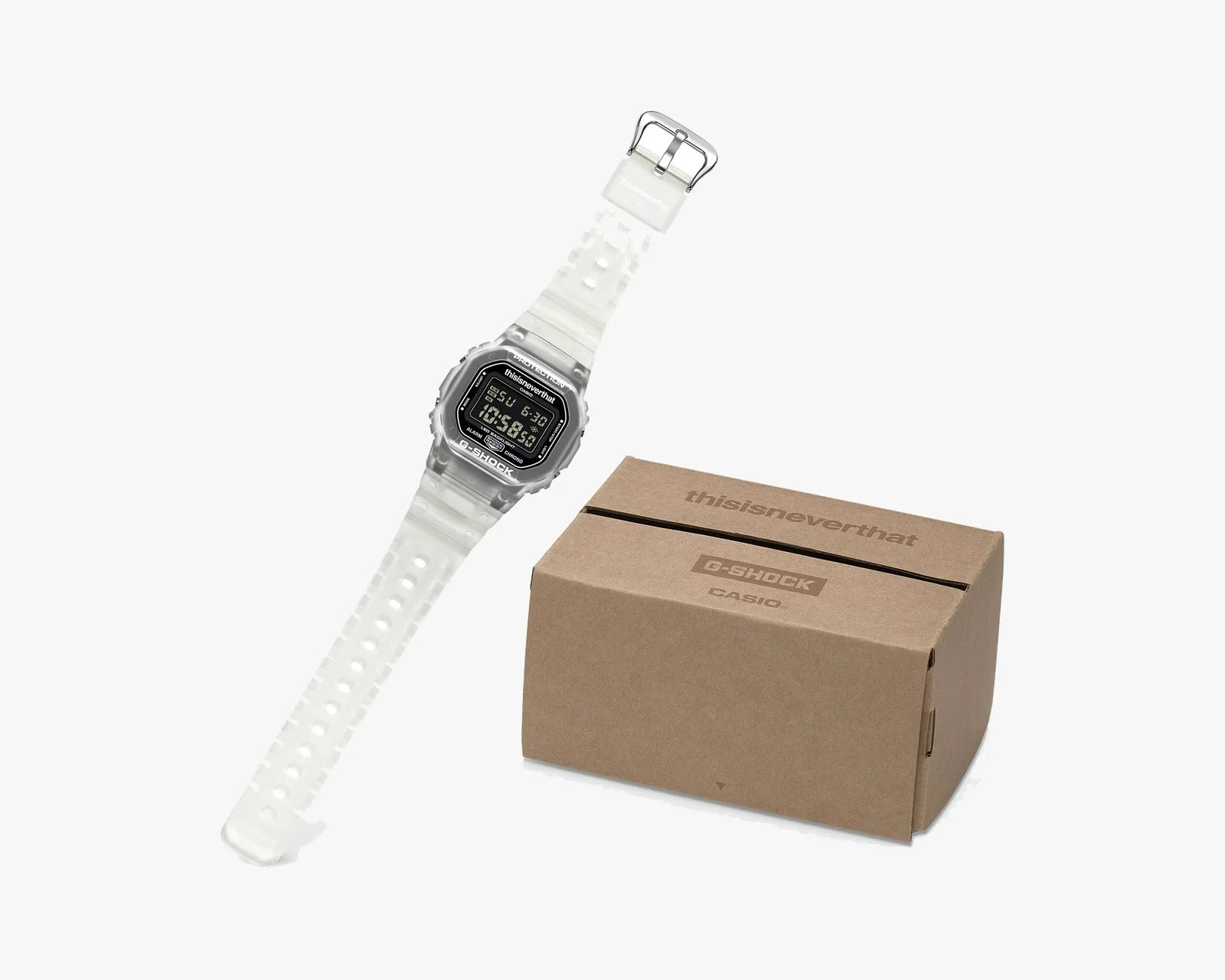 Transparent white G-Shock digital watch with black face and silver buckle next to a brown cardboard box with "thisisneverthat" and "G-SHOCK CASIO" logos.